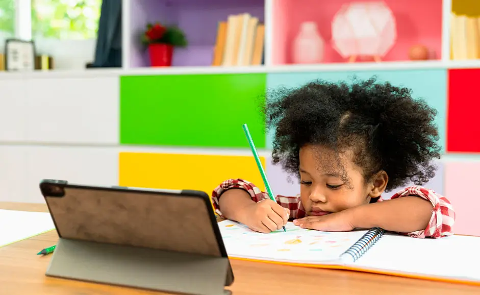 A child practising writing on a worksheet at a desk